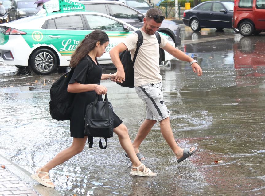 FOTO/ Njerëz që kapërcejnë rrugët e mbushura plot me ujë, shiu “pushton” Tiranën